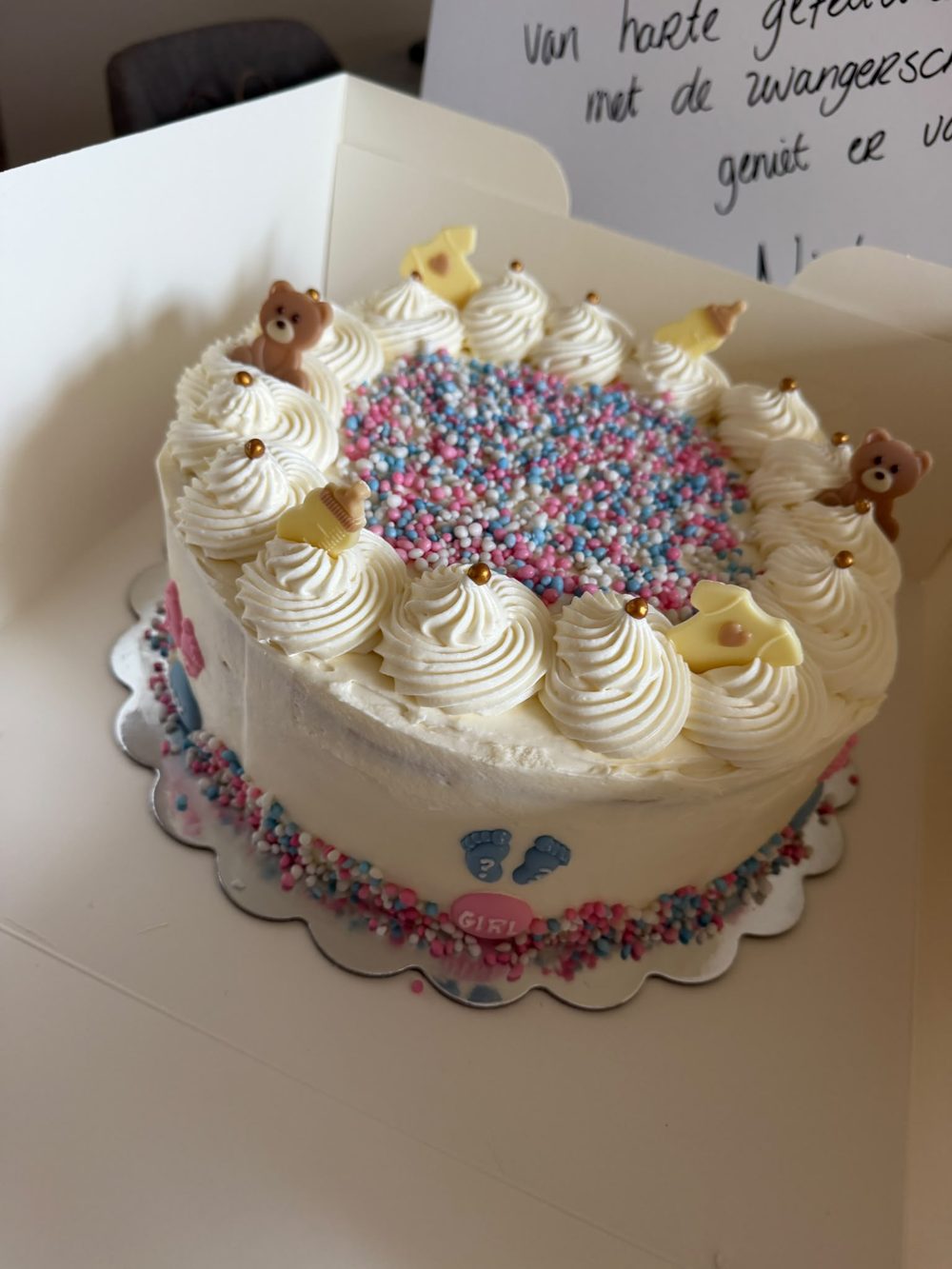 Gender reveal taart met roze en blauwe muisjes, beertjes en slagroomtoefjes